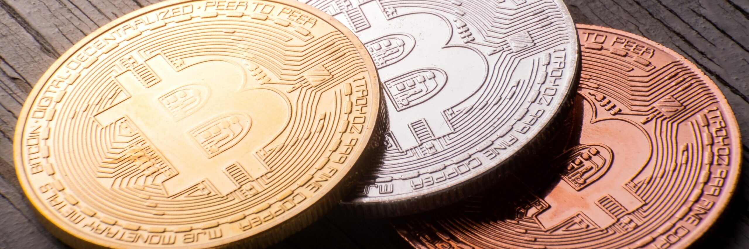Closeup shot of gold, silver, and bronze bitcoin in a wooden surface