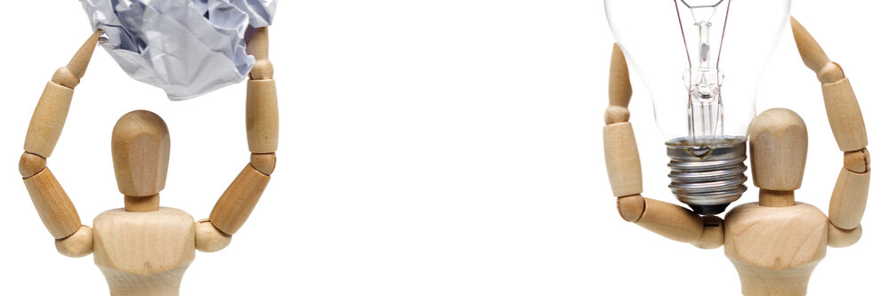 Two,Wood,Figure,Mannequins,Carrying,An,Incandescent,Light,Bulb,And