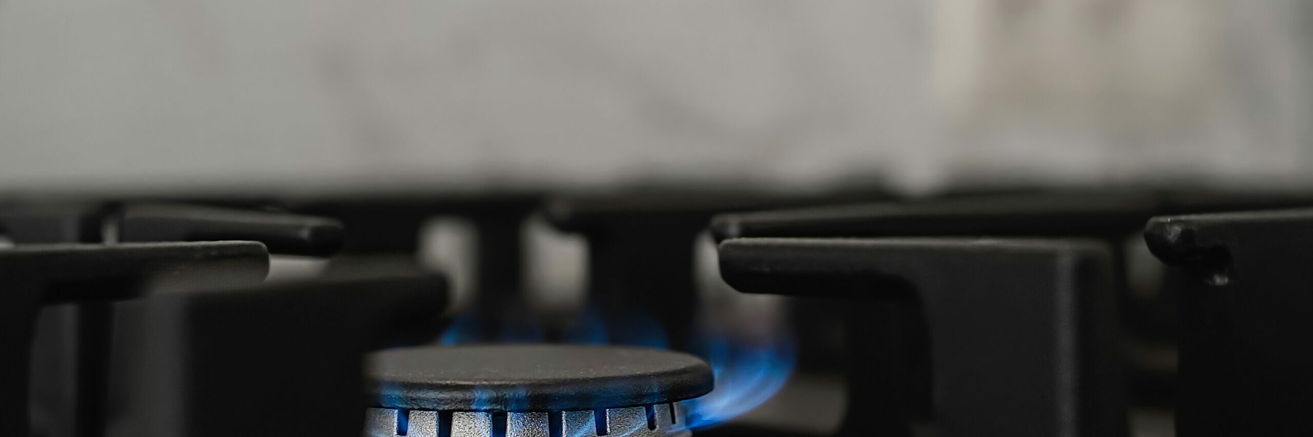 Modern kitchen stove, natural gas burns with a blue flame. Household gas consumption. Close-up, selective focus